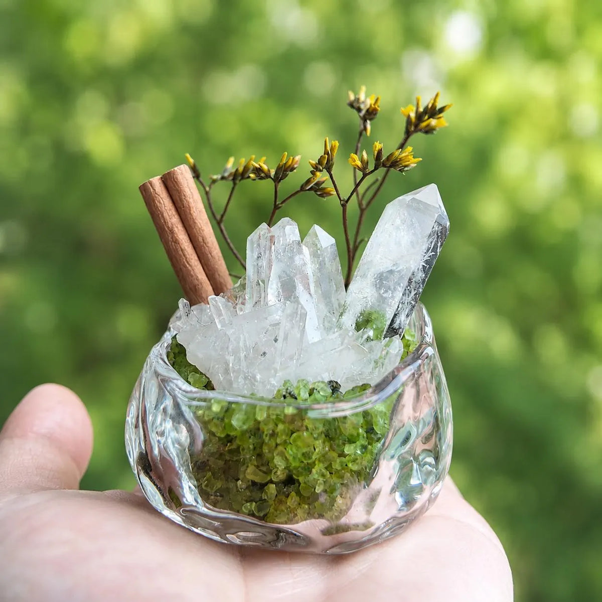 Miniature quartz and peridot garden held in a hand to show its small size.
