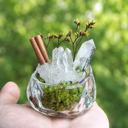 Miniature quartz and peridot garden held in a hand to show its small size.